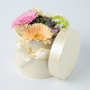 Pastel bloemstukje in stoffen hoedendoosje ingezoomd