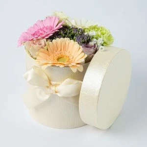 Pastel bloemstukje in stoffen hoedendoosje ingezoomd