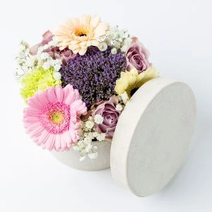 Pastel bloemstukje in stoffen hoedendoosje ingezoomd